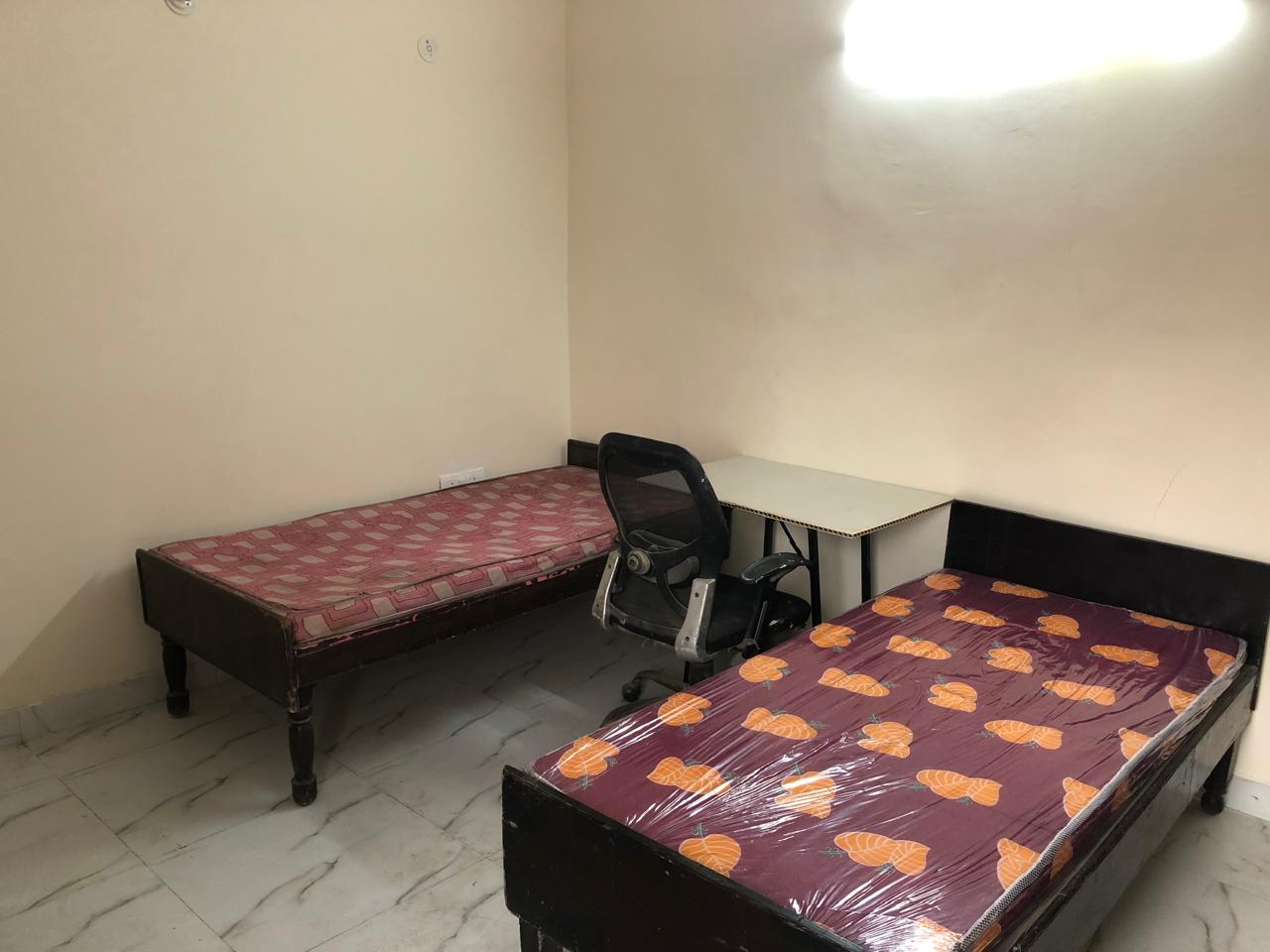 Crystal Stay PG room with two beds and study table